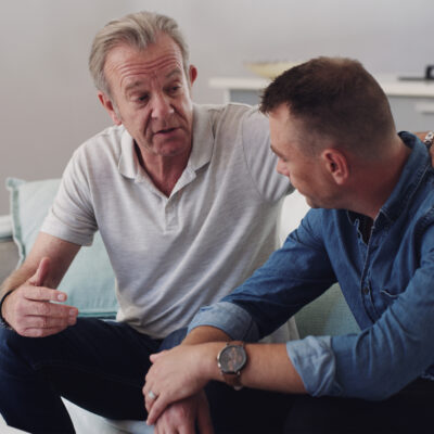 Sofa, old man and adult son bonding together in living room, conversation and support in home. Love, relationship and senior dad with man on couch, relax and discussion, family connection and advice.